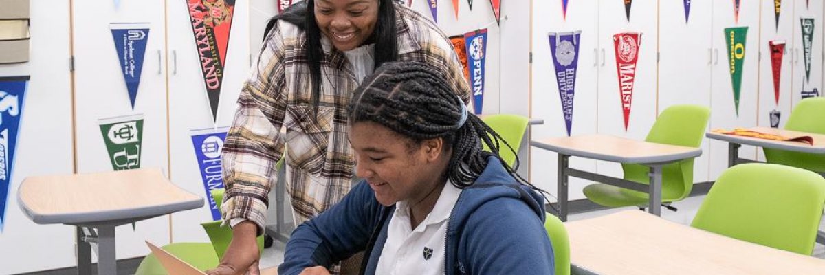 Teacher helping student on a laptop in a classroom